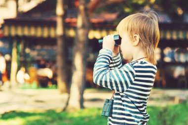 Sevimli küçük bir çocuk açık dürbün ile seyir.