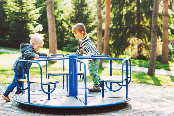 Zwei glückliche Jungen, die auf einem Spielplatz in einem Park spielen. — Stockfoto