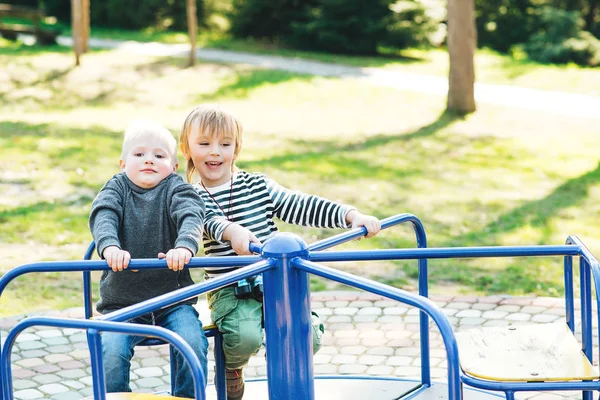 Zwei glückliche Jungen, die auf einem Spielplatz in einem Park spielen. — Stockfoto