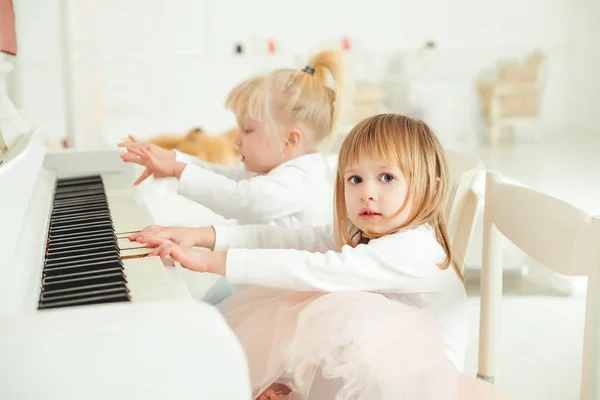 Two cute little girls playing piano in a studio. — Stock Photo, Image