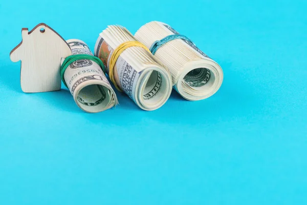 Het concept van financiële besparingen om een huis te kopen. Mini model huis, dollar op rollen, geïsoleerd op blauwe achtergrond. — Stockfoto