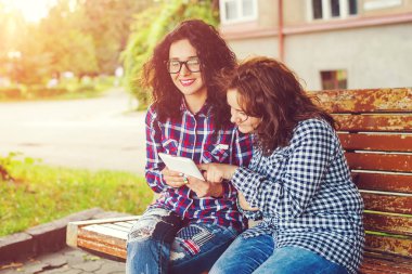 Tablet bilgisayar açık havada kullanarak iki genç kadın.