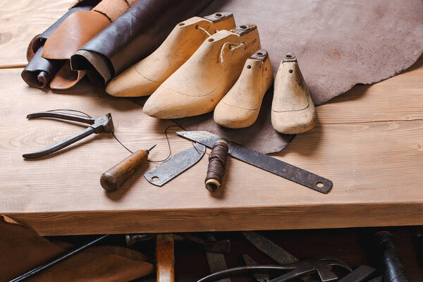 Leather in rolls, cobbler tools and shoe lasts in workshop. Leat