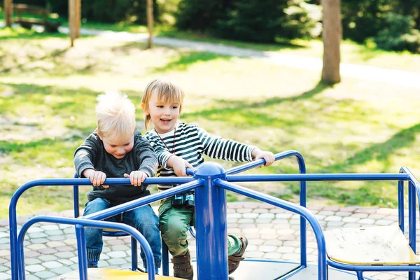 Zwei glückliche Jungen, die auf einem Spielplatz in einem Park spielen. — Stockfoto