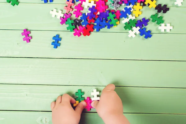 Een heleboel puzzels op houten tafel. Kind verbindt puzzels. — Stockfoto