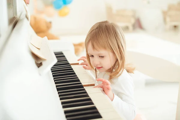 Ładna dziewczynka gry na fortepianie w pokoju światło. — Zdjęcie stockowe
