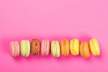 Pembe bir arka plan üzerinde üstten görünüm renkli macaron veya acıbadem kurabiyesi. Sayfanın Üstü