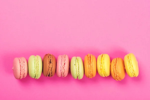 Draufsicht auf bunte Macaron oder Makronen auf rosa Hintergrund. oben — Stockfoto
