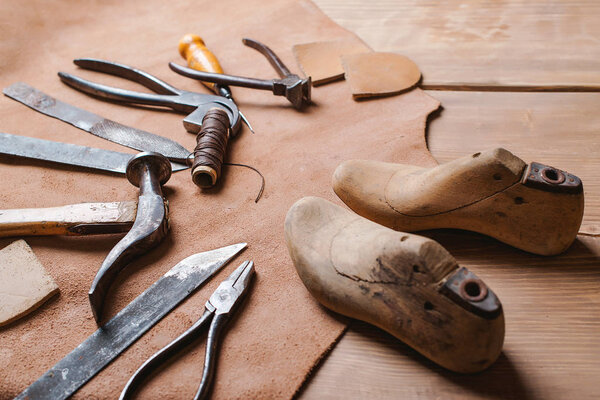Cobbler tools in workshop on the wooden table .