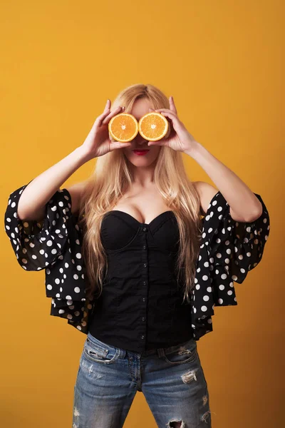 Glückliche junge Frau mit Orangenhälften auf gelbem Hintergrund. — Stockfoto