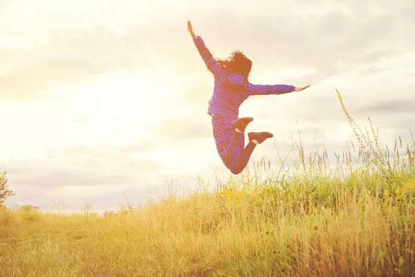 Молода жінка стрибає проти заходу сонця в природі  . — стокове фото