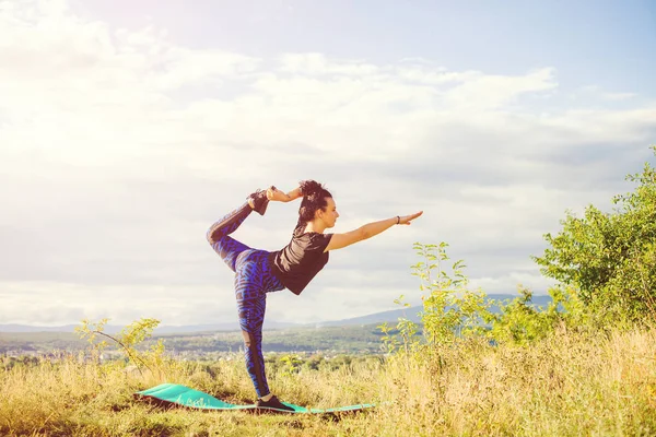 Junge Frau macht Yoga oder Fitnessübungen im Freien, Naturlandschaft bei Sonnenuntergang. — Stockfoto