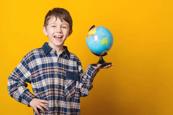 Портрет маленького милого мальчика с глобусом. Изолированный на жёлтом фоне . — стоковое фото