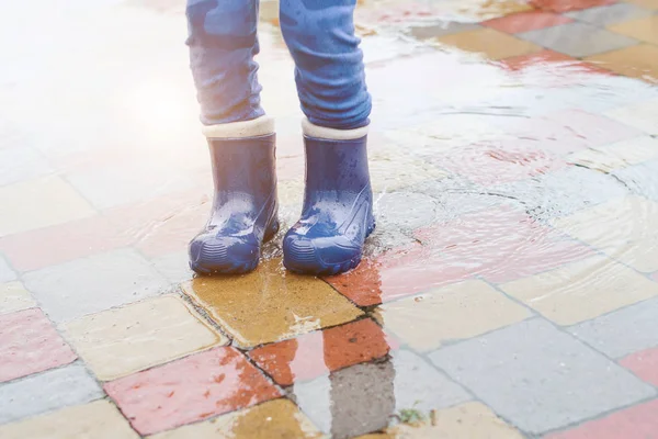 Pies de niño en botas de goma saltando en un charco después de la lluvia . — Foto de Stock