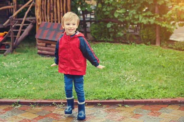 Joyeux garçon sautant dans les flaques après la pluie . — Photo