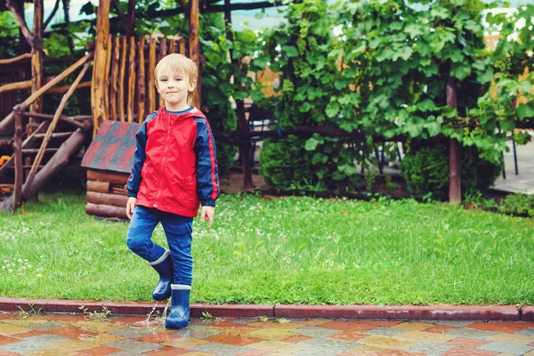 Szczęśliwy chłopiec skoki w kałuże po deszczu. — Zdjęcie stockowe