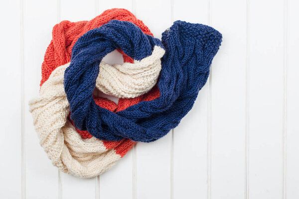 Colorful woolly hat and scarf on white wooden background.