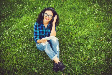 Tablet pc ve müzik açık havada için dinlerken kulaklık kullanarak mutlu güzel kız.