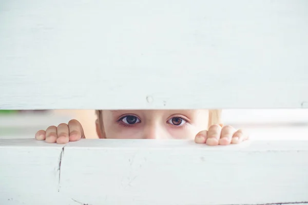 Triste petit garçon regarde à travers la fente de la clôture, vue depuis l'embuscade . — Photo