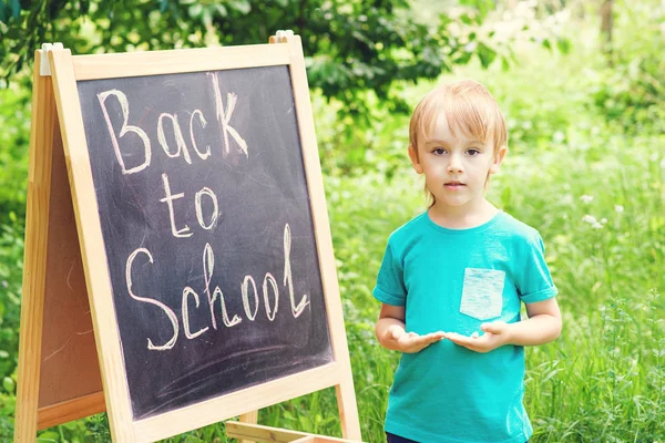 Bel bambino che scrive sulla lavagna all'aperto. Concetto di ritorno a scuola . — Foto Stock