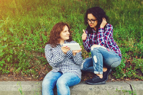 Twee jonge vrouwen buitenshuis gebruik van tablet pc. — Stockfoto