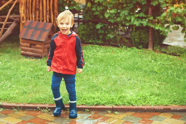 Niño feliz saltando en charcos después de la lluvia . — Foto de Stock
