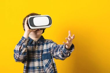 Sanal gerçeklik giysili oğlan sarı arka plan üzerinde koruyucu gözlük.