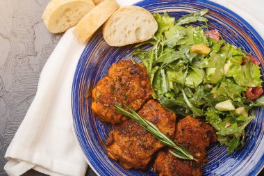 Platter of chicken thighs piri piri coated in hot sauce with salad. clipart