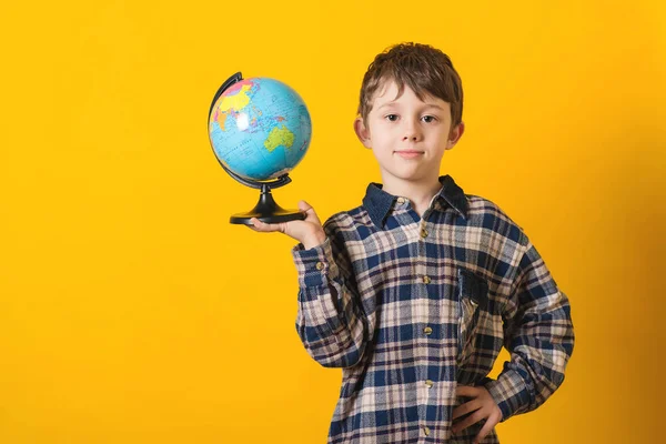 Portrét roztomilý chlapeček s zeměkoule. Na žlutém pozadí, samostatný. — Stock fotografie