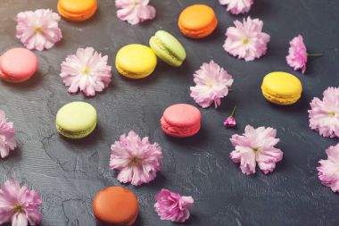 Renkli macaroons siyah artalanları üzerinde bahar sakura çiçekli. Seçici odak.