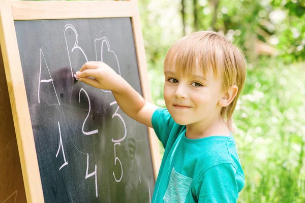 Cute little boy at blackboard practicing counting and math outdoor. — Stock Photo, Image