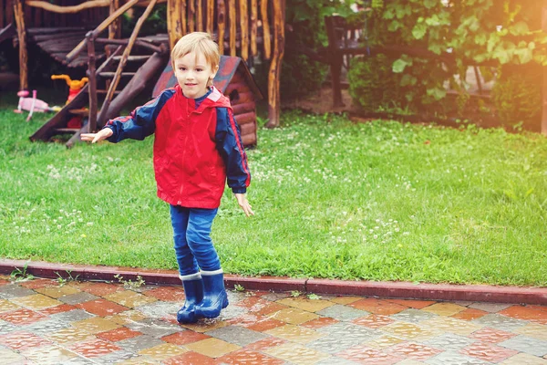 Ugrás a pocsolyák, eső után boldog fiú. — Stock Fotó