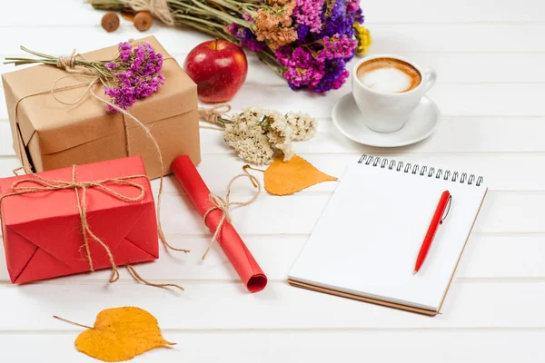 Caixas de presente de artesanato com tema de outono, folhas amarelas decoradas, flores. Uma xícara de cappuccino e caderno com lápis . — Fotografia de Stock