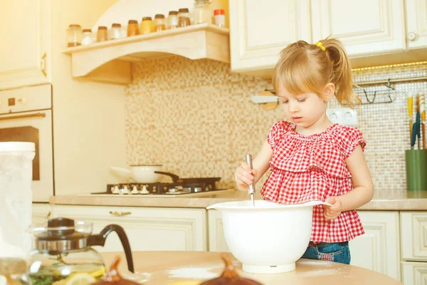 Cute little helper girl helping her mother cooking in a kitchen. Happy loving family are preparing bakery. — Stock Photo, Image