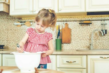 Sevimli küçük yardımcısı kız annesi bir mutfak pişirme yardım. Mutlu sevgi dolu aile ekmek hazırlama.