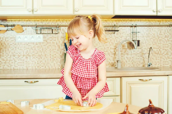 Carino bambina aiutando sua madre cuocere i biscotti in una cucina . — Foto Stock