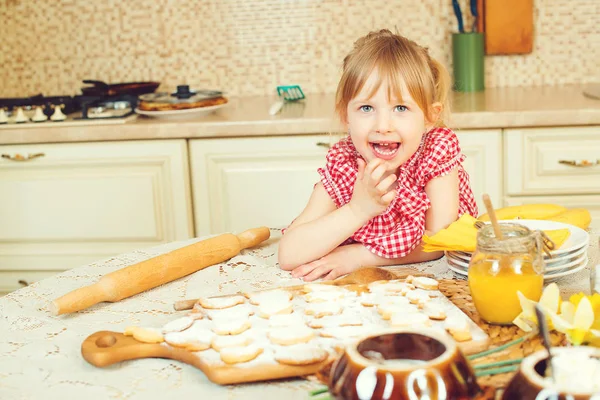 Carino bambina aiutando sua madre cuocere i biscotti in cucina . — Foto Stock
