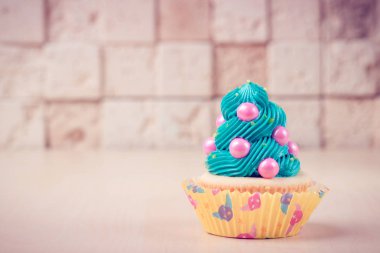 Masanın üstüne tuğla duvar arka plan üzerinde renkli cupcake.