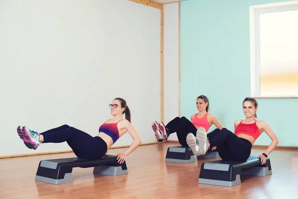 Gruppe junger Sportlerinnen trainiert mit Stepper im Fitnessstudio. — Stockfoto