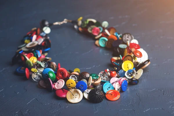 Jóias artesanais feitas de botões coloridos de plástico no fundo preto . — Fotografia de Stock