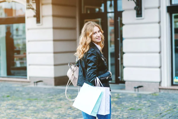 Mujer joven y feliz con bolsas de compras caminando por la calle . — Foto de Stock