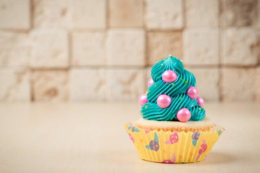 Masanın üstüne tuğla duvar arka plan üzerinde renkli cupcake.