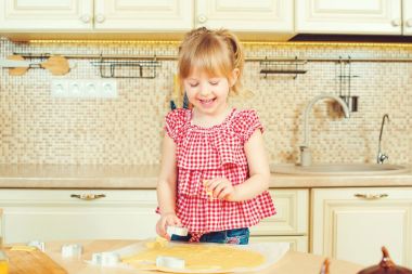 Sevimli küçük kız onun annesi fırında çerezleri bir mutfakta yardım.