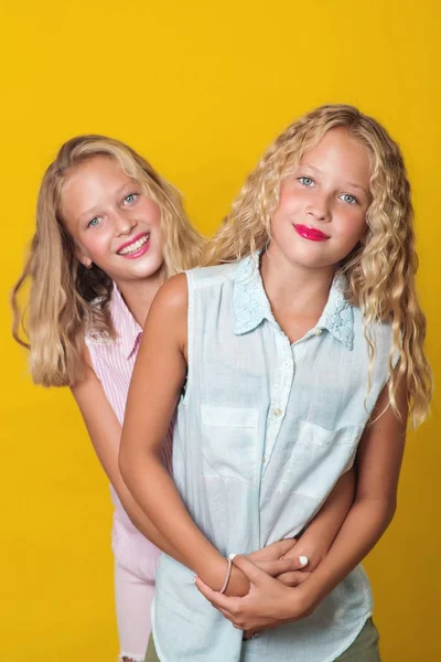 Gemelos adolescentes divirtiéndose juntos, aislados sobre un fondo amarillo . — Foto de Stock