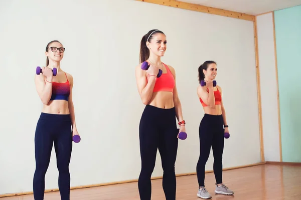Gruppe junger Frauen in Sportbekleidung mit Kurzhanteln beim Training im Fitnessstudio. — Stockfoto