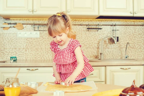 Carino bambina aiutando sua madre cuocere i biscotti in una cucina . — Foto Stock