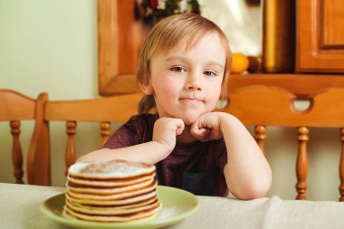 Sevimli küçük çocuk bir yığın krep mutfakta yemek.
