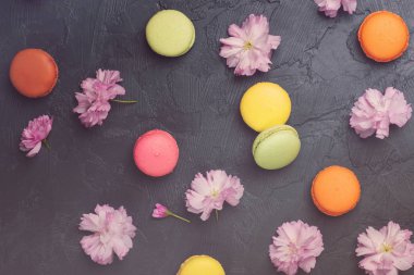 Renkli macarons siyah artalanları üzerinde bahar sakura çiçekli. Üstten Görünüm.