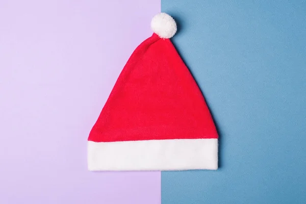 Santa Claus red hat on blue and wiolet paper background , minimal style. — Stock Photo, Image