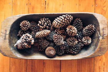 Birçok çam kozalakları masada eski ahşap kase.